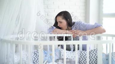 不开心的女人。 年轻的母亲，烦恼，疲惫的女人睡在婴儿床旁。