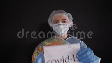 穿着防护服的女人拿着一个牌子，上面写着covid-19。 女孩拿着一个地球模型，一个地球仪。