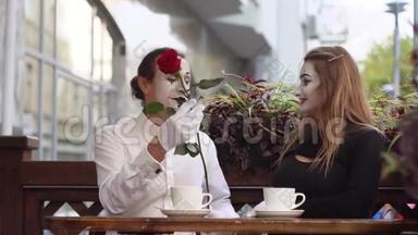 两个快乐的哑剧在咖啡馆里约会。 快乐的男人给他的女朋友送花。 浪漫的约会