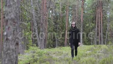 孤独的黑衣人穿过树林，前面的风景。 他感到轻松、思考和无聊