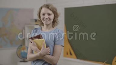 女学生或女教师在教室里拿书。 准备上学了。 微笑女<strong>讲师</strong>