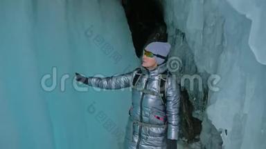 在贝加尔湖冰洞旅行的女人。 去冬岛旅行。 女孩背包客正在冰窟散步。 旅行者看起来