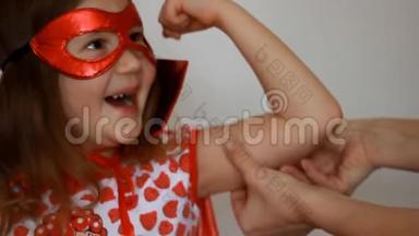 小女孩扮演超级英雄。 有趣的孩子穿着红色雨衣和面具玩权力超级英雄。 超级英雄和权力