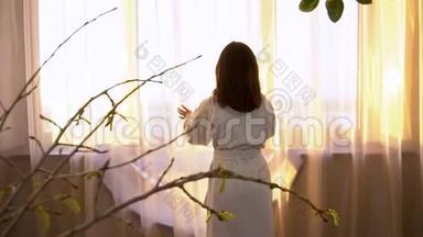 一个穿着白大褂的年轻女子走到窗边拉开窗帘.. 早晨的女孩望着窗外