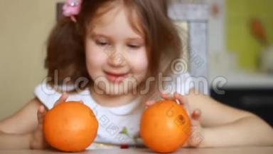 在孩子的手里合上橙色。 小女孩在玩两个橘子。 健康食品。 水果中的维生素。 维生素C