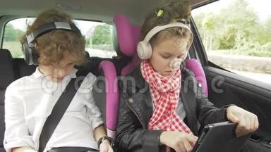 男孩和女孩带着耳机在汽车上玩平板电脑和智能手机，孩子们在汽车上使用设备。 <strong>兄弟</strong>和<strong>兄弟</strong>