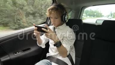 带着耳机的十几岁男孩坐在带<strong>安全带</strong>的车里，用智能手机