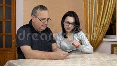 女儿教父亲如何使用电话。 一个年轻的女人告诉她的老父亲在哪里推电话。 家庭是