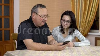 女儿教父亲如何使用电话。 一个年轻的女人告诉她的老父亲在哪里点击智能手机。 那个人