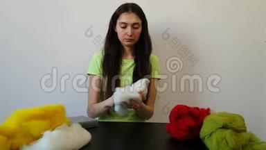 一个黑发女人在家做针线活。 一个严肃的女孩创造了一个羊毛玩具。 从羊毛中干毡。 有趣的爱好