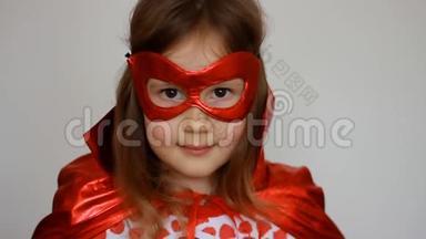 小女孩扮演超级英雄。 有趣的孩子穿着红色雨衣和面具玩权力超级英雄。 超级英雄和权力概念
