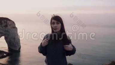 美丽平静的旅游女子看着相机，转身看着<strong>绚丽</strong>的日落，在埃特雷特悬崖上观看缓慢的运动。
