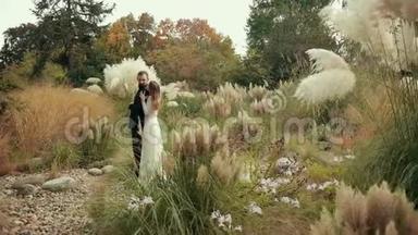 年轻的一对新娘拥抱在美丽的花园里毛茸茸的<strong>嫩草</strong>。