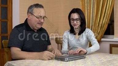 女儿教父亲<strong>如何</strong>使用笔记本电脑。 一个年轻的女人向她的老父亲展示了<strong>如何</strong>打开笔记本电脑。 家庭是