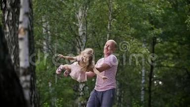 在公园里和爸爸在一起的小女孩-爸爸在旋转她的小女孩，慢动作