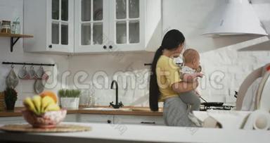 年轻的妈妈抱着孩子做家务