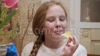 肖像少年女孩在家厨房吃<strong>薯片</strong>。 特写脸上雀斑的少女在吃脆片