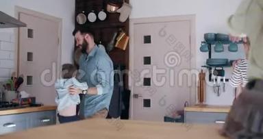 快乐的年轻白种人父亲抓住快乐的小儿子跳在他的怀里，家庭娱乐时间在厨房慢动作。