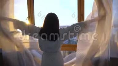 一个穿着白大褂的年轻女子走到窗边拉开窗帘.. 早晨的女孩望着窗外