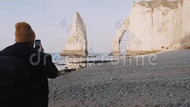 快乐男摄影师拍摄智能手机照片，走向著名的Etretat海边白色悬崖拱门慢动作。