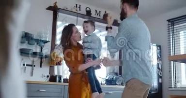快乐的年轻白种人的母亲和父亲享受玩耍和跳舞与小可爱的儿子在家里慢动作。