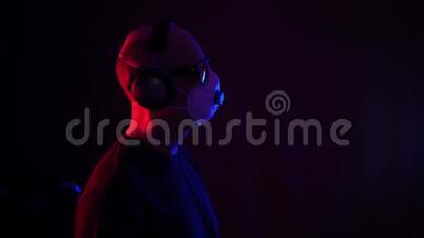 戴防护面罩的人在霓虹灯背景下听<strong>音乐耳机</strong>。 听<strong>耳机音乐</strong>的人