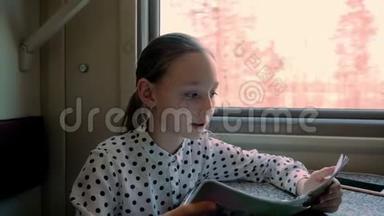 年轻女孩十几岁，在窗口背景下一边看火车。 一个十几岁的旅游女孩在窗边的火车上看书