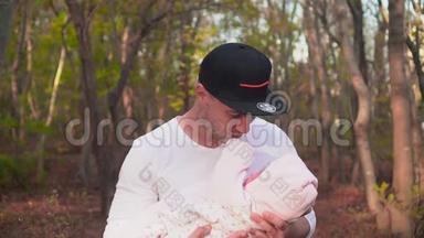 快乐的年轻人抱着一个小女孩在他的怀里微笑。 幸福的父亲怀里抱着一个小女儿..