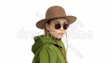 在绿皮大衣和帽子的工作室里，一个秋天看的女人转身向镜头摆姿势