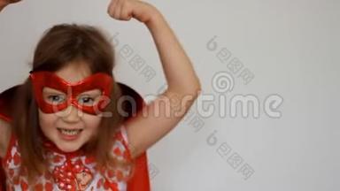 小女孩扮演超级英雄。 有趣的孩子穿着红色雨衣和面具玩权力超级英雄。 超级英雄和权力概念