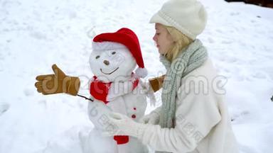可爱的女孩在雪亮的地方堆雪人。 冬季户外活动圣诞情感..