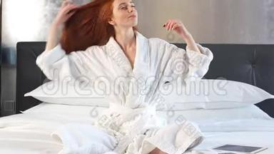红发女孩穿着<strong>白色浴袍</strong>躺在酒店房间的床上。