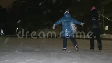 在下雪的时候，妈妈和女儿一起在冬季公园的冰场上溜冰。 母亲和少女