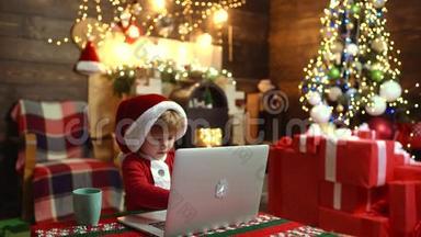 可爱的孩子带着笔记本电脑在家里的圣诞节背景。 圣诞快乐，孩子新年快乐。 圣诞礼物