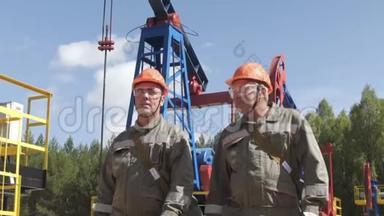两名石油工人监督<strong>原油</strong>生产钻机。 工业油井泵千斤顶用于抽取<strong>原油</strong>