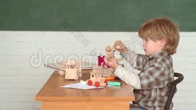 喜笑颜开的小学生在书桌前.. 孩子在课堂上以黑板为背景学习。 学校里的小孩子