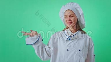一个漂亮的女士面包师穿着制服，戴着一个绿色的大背景色键概念，用手指打字