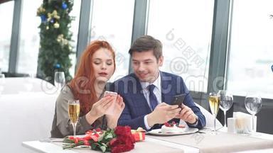 年轻的欧洲夫妇在餐馆<strong>约会</strong>。 红发女孩在他的智能<strong>手机</strong>上显示一个男人的照片