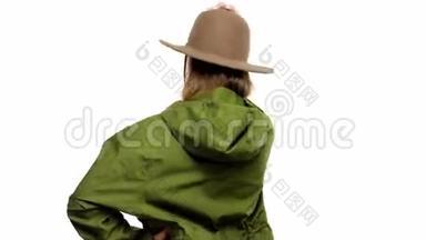 在绿皮大衣和帽子的工作室里，一个秋天看的女人转身向镜头摆姿势