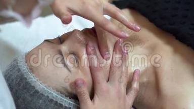 按摩治疗师正在对客户`面部进行手动按摩。 水疗面部按摩