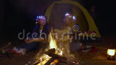 晚上，妈妈和女儿在露营地用吉他前篝火演唱歌曲。 女儿一起玩音乐唱歌