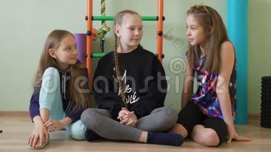 十几岁的女孩坐在<strong>学校体育</strong>馆的地板上。 <strong>学校</strong>女朋友一起在健身房聊天。