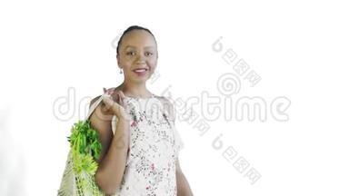 漂亮的美国黑人妇女手里拿着可重复使用的网状编织购物袋，里面有<strong>水果</strong>、<strong>蔬菜</strong>和<strong>蔬菜</strong>