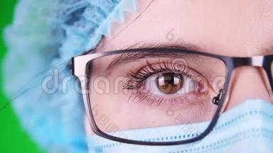绿色背景。特写镜头，眼睛，部分女医生脸戴眼镜，戴蓝色医用面罩和医用帽。