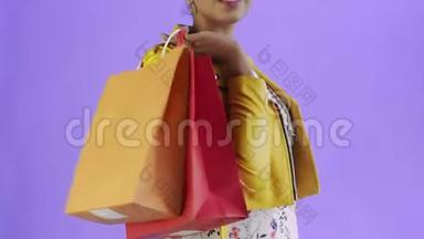 画室里紫色背景的非洲裔美国妇女的画像，她拿着购物袋和钱扇。黄色夹克