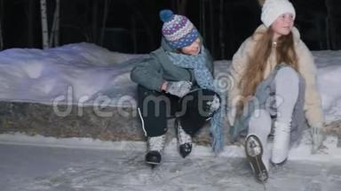 在公园的冬天晚上，十几岁的男孩和女孩在<strong>溜冰</strong>场上滑冰后休息。 穿着<strong>溜冰</strong>鞋的女孩和男孩
