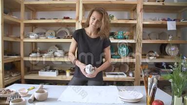 年轻女子在一家时尚的陶瓷工作室工作。一个小女孩手里拿着一个陶土块，揉着陶土