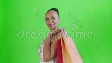 一位非洲裔<strong>美国</strong>妇女正在摄影棚里摆着绿色背景的<strong>购物</strong>袋。快乐女人<strong>购物</strong>五彩缤纷