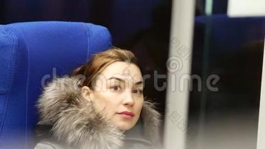 坐着漂亮的女士坐在莫斯科的地铁车厢里，<strong>看</strong>着<strong>窗外</strong>