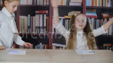 可爱的快乐<strong>嬉戏</strong>的女学生在图书馆的书桌前跳舞